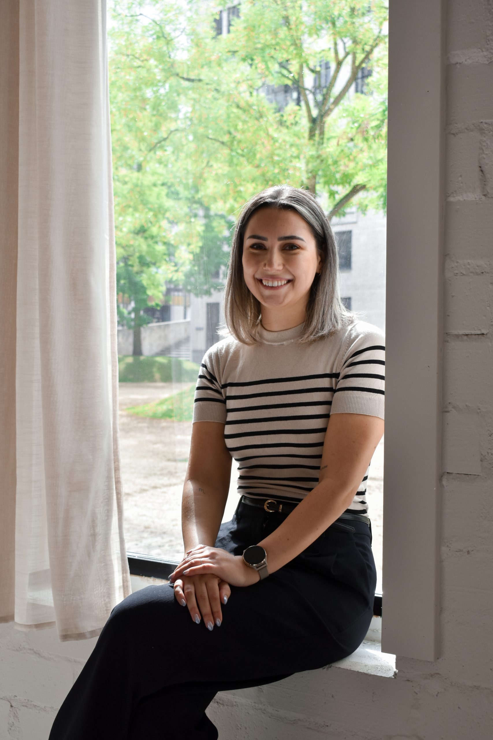 Sylke Preud’homme, virtual assistant, portret zittend bij raam met groene achtergron