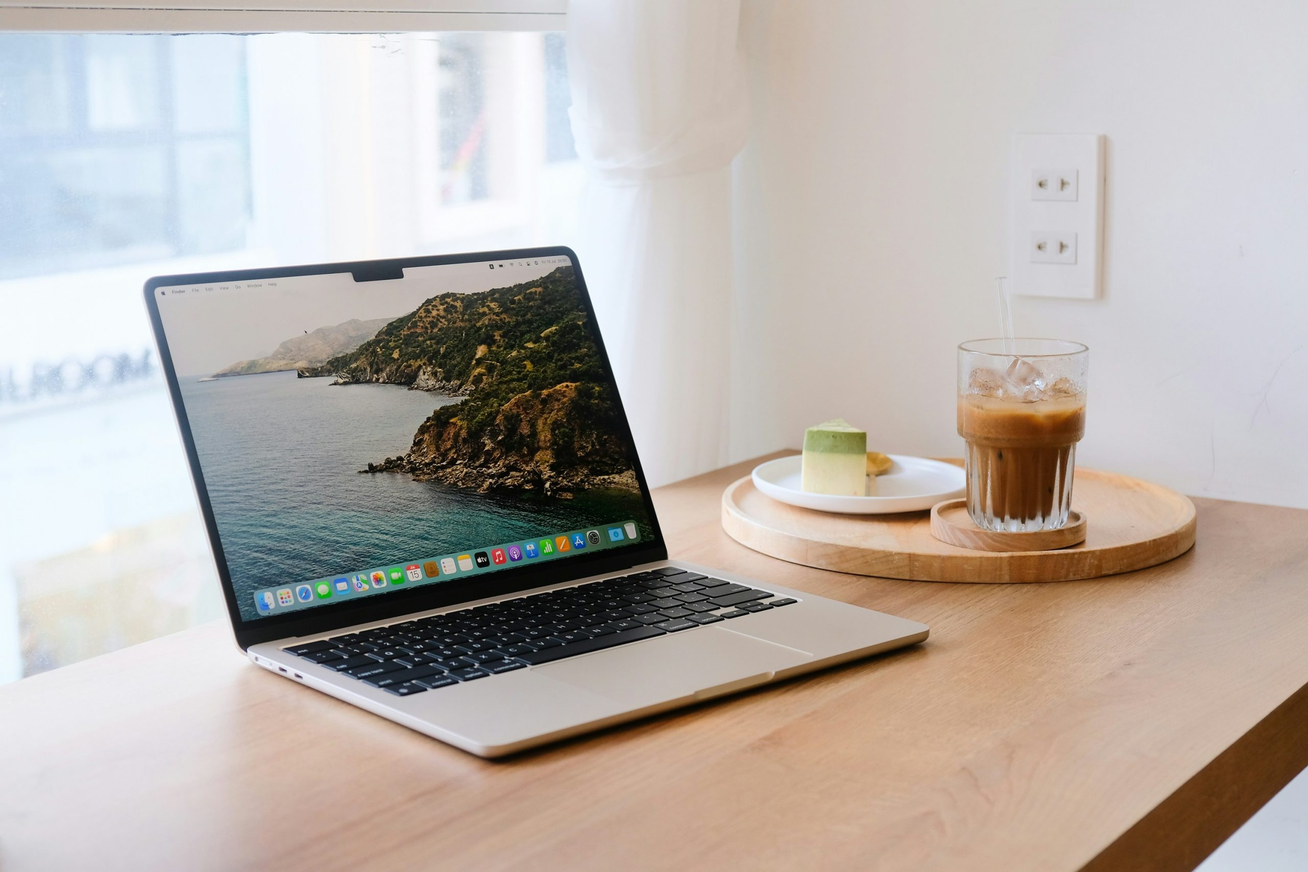 Minimalistische werkplek met een gesloten MacBook, houten bureaustandaard en strak georganiseerde accessoires – een rustige, gestructureerde backoffice setting.